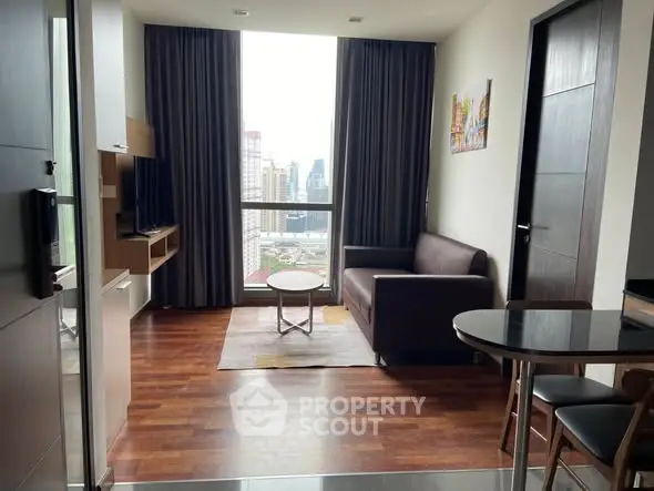 Modern living room with city view, featuring sleek furniture and large windows for natural light.