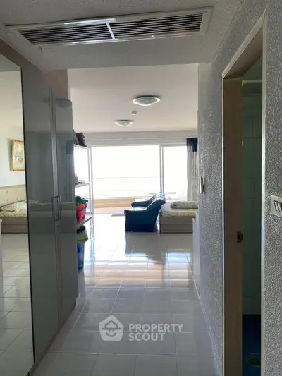 Spacious apartment hallway leading to a bright living room with large windows and balcony view.