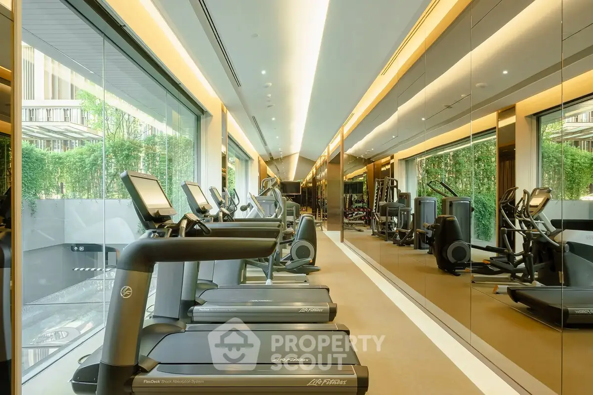 Luxurious gym with modern equipment and mirrored walls in upscale residential building.
