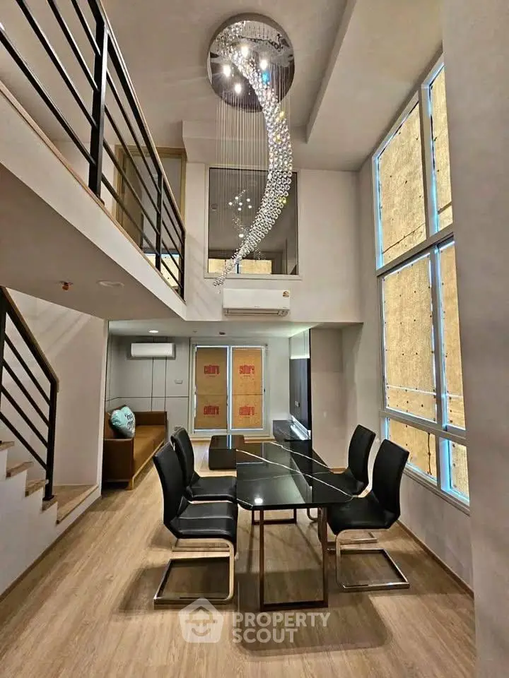 Stunning modern dining area with high ceilings and elegant chandelier in a duplex apartment.