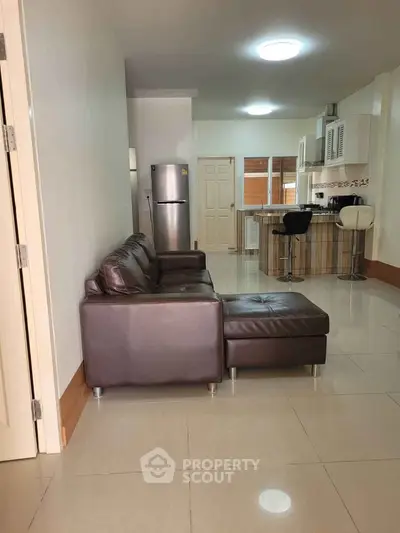 Modern open-layout living room with leather sofa and sleek kitchen area