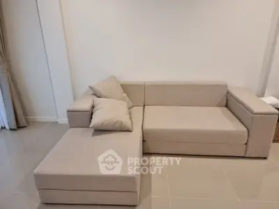 Modern living room with stylish beige sectional sofa and elegant tile flooring.