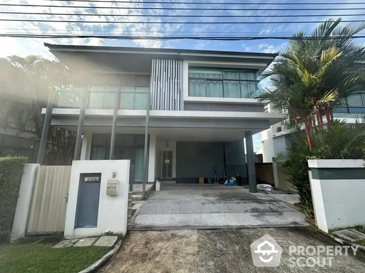 Modern two-story house with large windows and driveway in a suburban neighborhood.