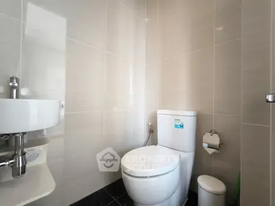 Modern bathroom with sleek fixtures and neutral tiles, featuring a compact design for efficient use of space.