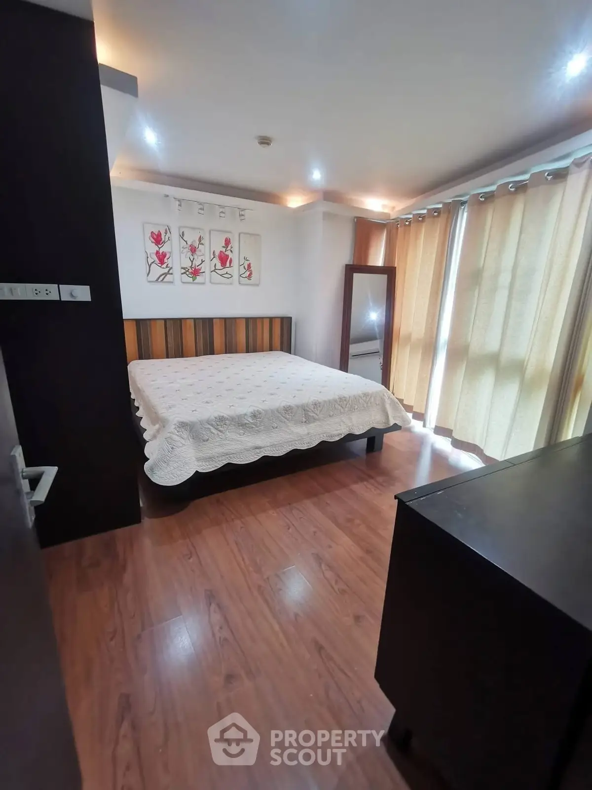 Spacious bedroom with wooden flooring and elegant decor