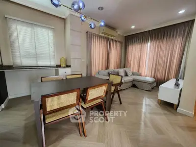Spacious living room with modern dining area and cozy seating, featuring elegant lighting and large windows.