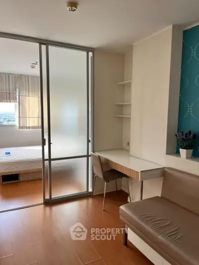 Modern studio apartment with sliding glass partition and cozy furnishings.