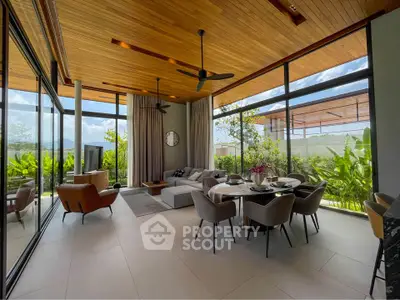 Luxurious open-plan living and dining area with floor-to-ceiling windows and garden view.