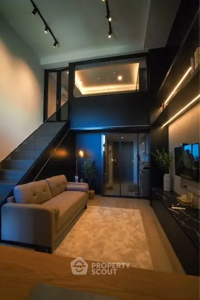 Modern living room with high ceiling and mezzanine, featuring elegant lighting and stylish decor.