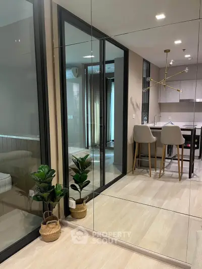 Modern open-layout kitchen with stylish lighting and mirrored wall, enhancing spaciousness and elegance.