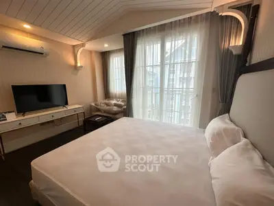 Spacious bedroom with modern decor and large windows for natural light.
