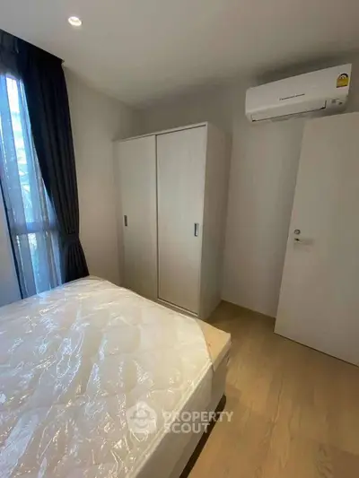 Cozy bedroom with natural light, featuring a wardrobe and air conditioning for comfort.
