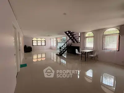 Spacious open-plan living room with modern staircase and large windows