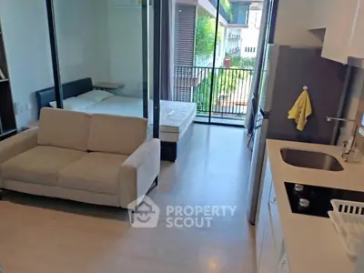 Modern studio apartment with open layout, featuring a cozy living area, compact kitchen, and balcony view.
