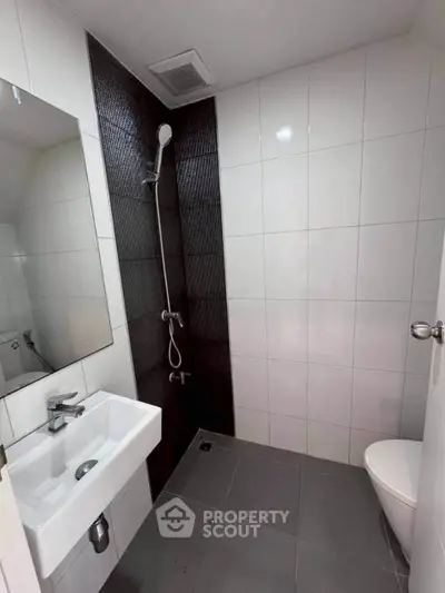 Modern bathroom with sleek design featuring a wall-mounted sink, shower, and toilet.