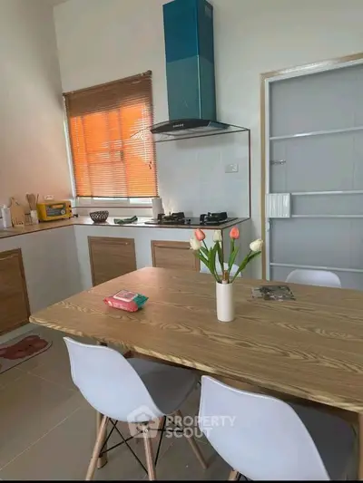 Modern kitchen with dining table and gas stove, featuring stylish decor and natural light.