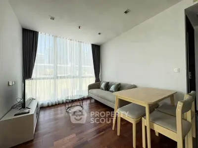 Modern living room with hardwood floors, large window, and minimalist furniture in a bright apartment.
