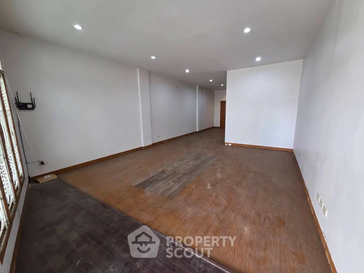 Spacious unfurnished room with wooden flooring and recessed lighting, ideal for customization.
