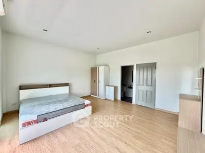 Spacious bedroom with modern furnishings and wooden flooring, ideal for comfort and relaxation.