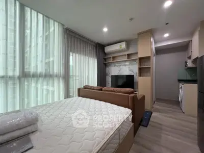Modern studio apartment with large windows and stylish furnishings in urban setting.