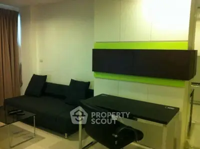 Modern living room with sleek black sofa and stylish desk, perfect for urban living.