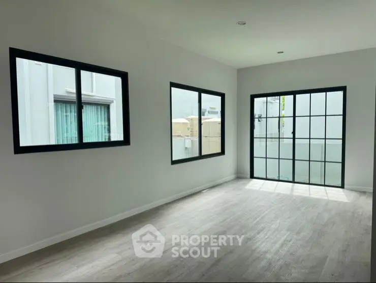 Spacious empty room with large windows and modern flooring, perfect for customization.