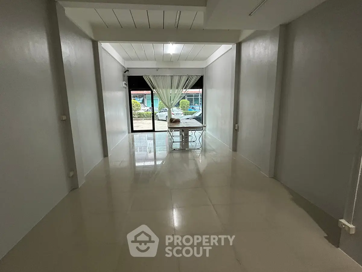 Spacious empty room with large window and tiled floor, ideal for customization.
