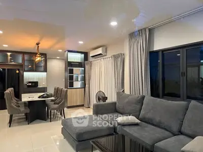 Modern living room with open kitchen, stylish furniture, and ambient lighting