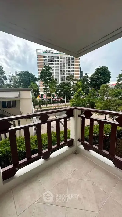Charming balcony with scenic view of lush greenery and modern building, perfect for relaxation.
