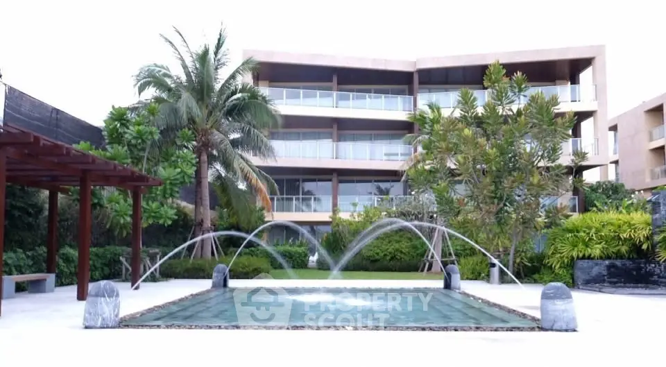 Luxurious apartment complex with lush landscaping and elegant water feature.