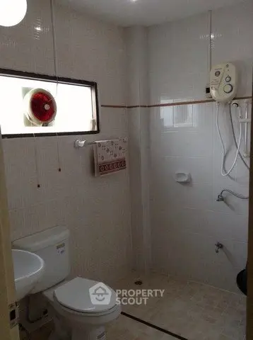 Compact bathroom with modern fixtures and natural light, featuring a shower and toilet.