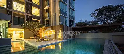 Luxurious apartment building with illuminated poolside at dusk, offering serene ambiance and modern architecture.