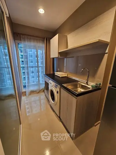 Modern kitchen with washing machine and sleek cabinetry in high-rise apartment