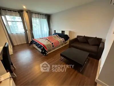 Spacious studio apartment with modern furnishings and large windows for natural light.