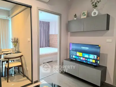 Modern living room with sleek TV setup and view into cozy bedroom