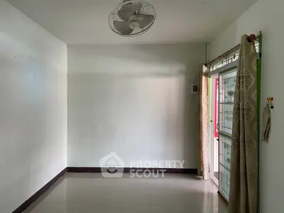 Spacious empty room with tiled floor and ceiling fan, ideal for customization.