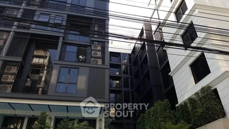 Modern urban apartment building exterior with sleek design and lush greenery.