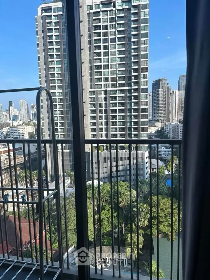 Stunning cityscape view from a high-rise balcony overlooking urban skyline and lush greenery.