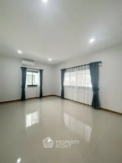 Spacious empty room with large windows and elegant curtains, perfect for customization.