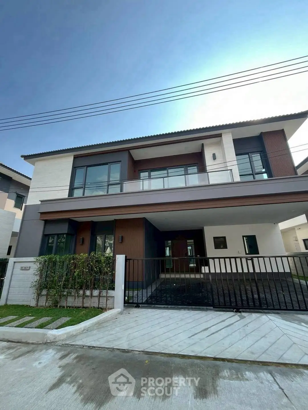 Modern two-story house with sleek design and spacious driveway in a suburban neighborhood.