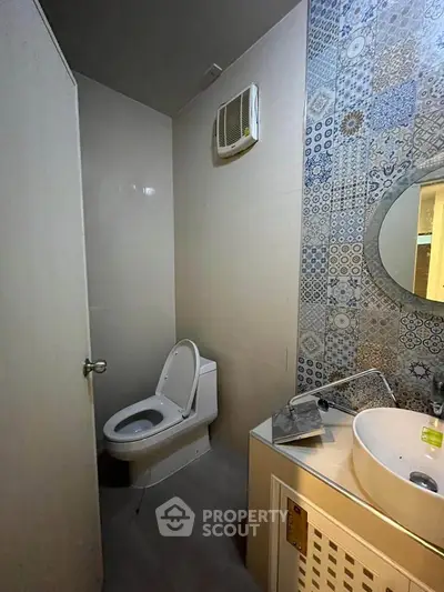 Modern bathroom with stylish tile accent wall and round mirror