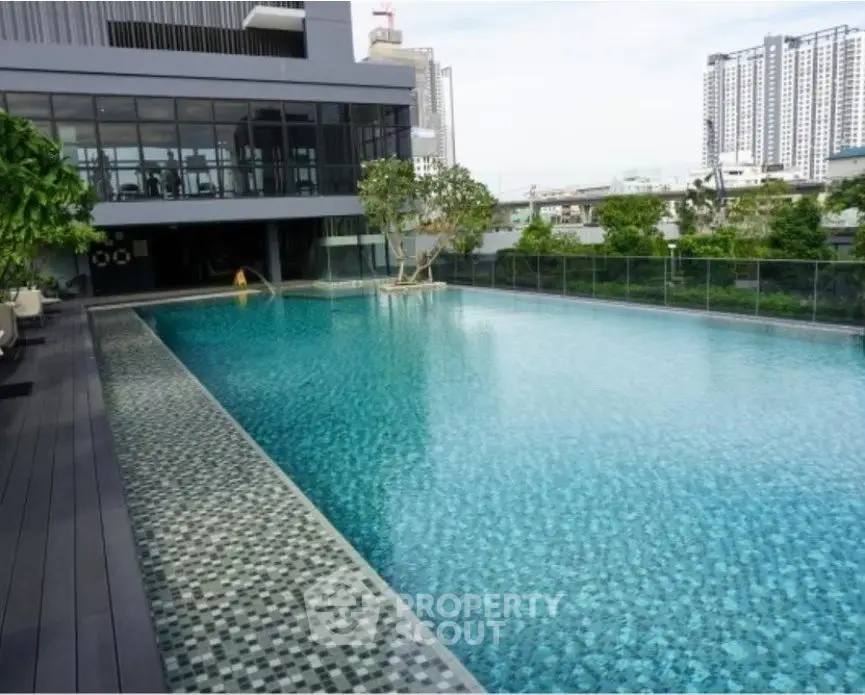 Luxurious rooftop pool with city skyline view in modern residential building.