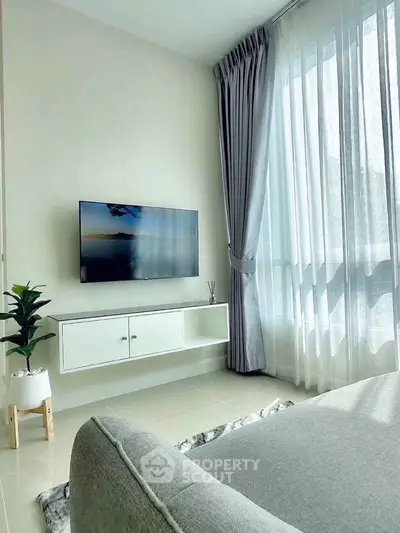 Modern living room with sleek TV setup and large window with elegant curtains.