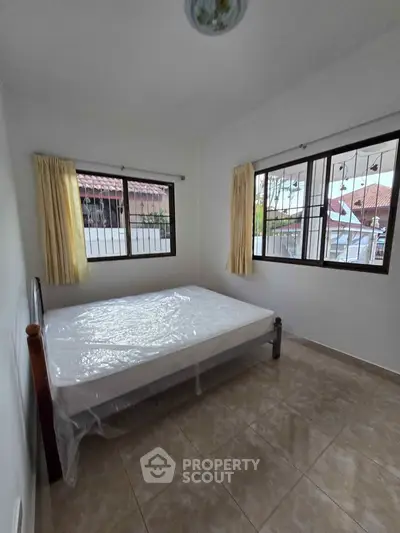 Cozy bedroom with natural light and tiled flooring, perfect for restful nights.