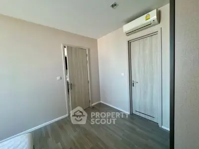 Minimalist bedroom with wooden flooring and air conditioning unit