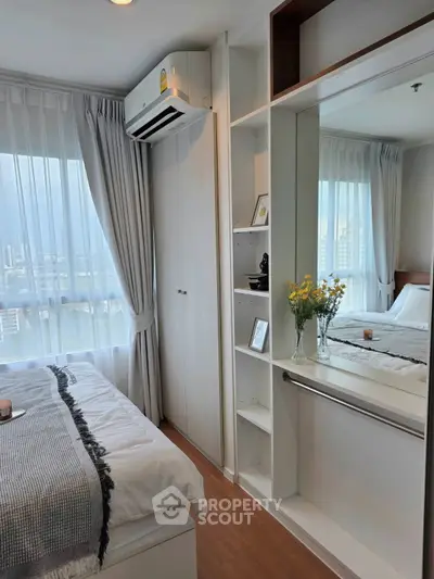 Modern bedroom with large window, built-in shelves, and air conditioning unit in a high-rise apartment.