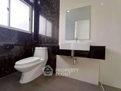 Modern bathroom with sleek black and white design, featuring a stylish sink and toilet.