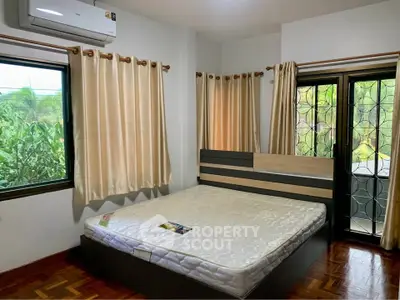 Spacious bedroom with large windows and balcony access, featuring a comfortable bed and air conditioning.