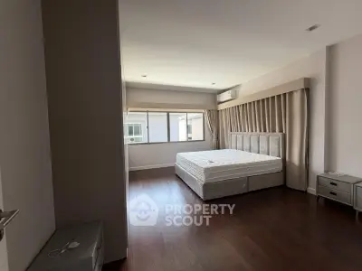 Spacious bedroom with hardwood floors and large window in modern apartment