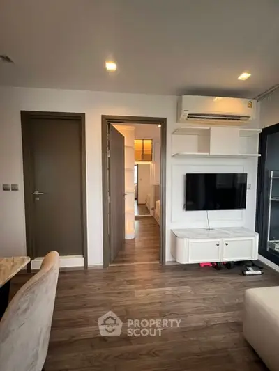 Modern living room with sleek TV setup and air conditioning in stylish apartment.